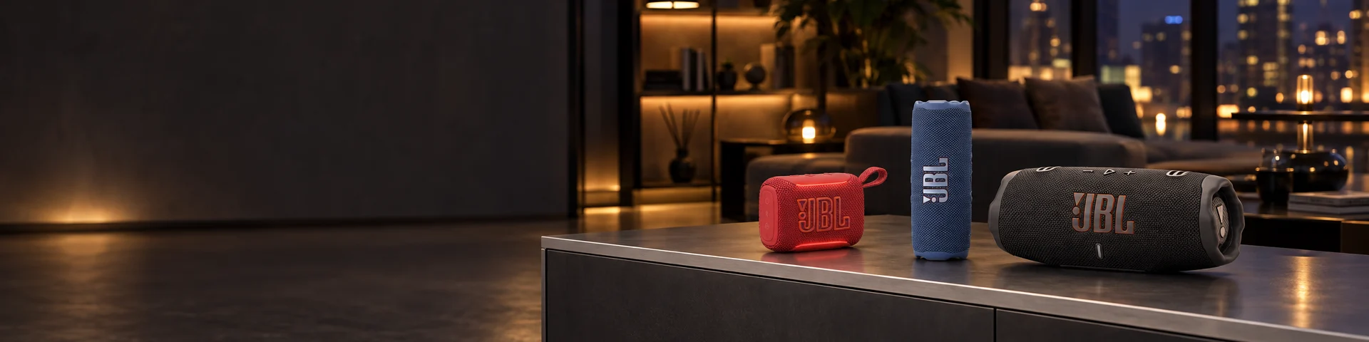 Tres parlantes JBL, uno rojo, uno azul y uno negro, sobre un aparador en una sala con vista a la ciudad